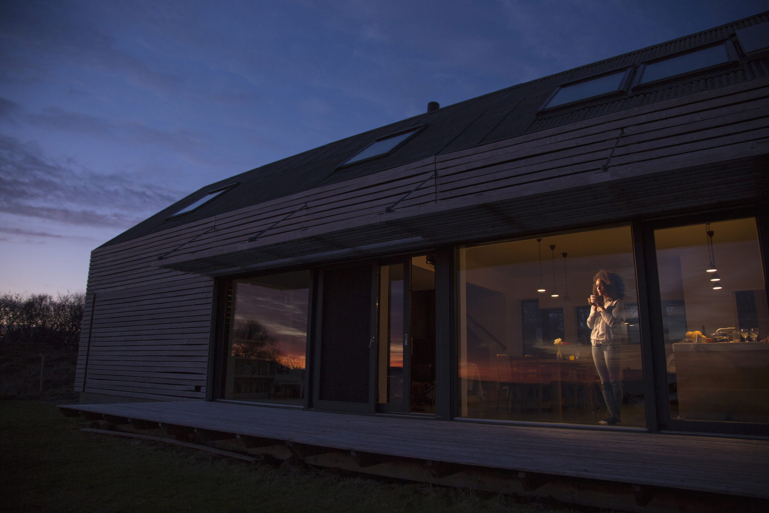 A serene twilight scene as a person reflects inside a modern home